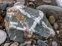 Grauer Stein mit breiter wulstartiger Maserung und rostfarbenen Sprenkeln